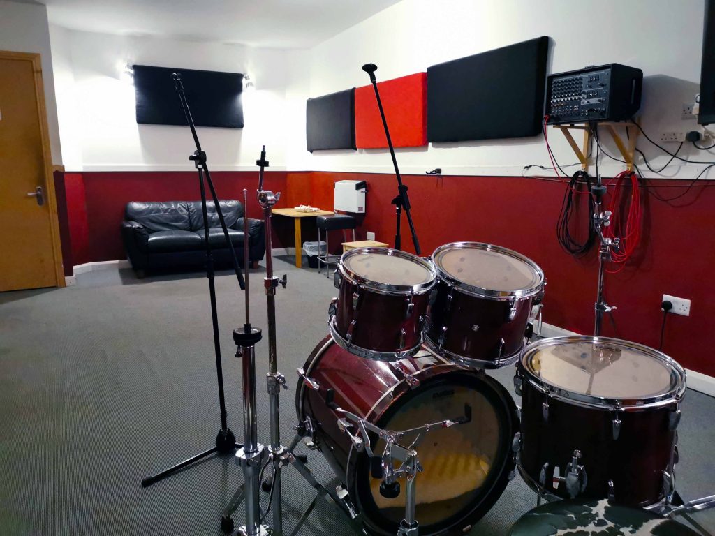 Mid size room with carpet floor. No mirror. EV/Yamaha PA & floor monitor. Pearl Masters rock/fusion size kit.