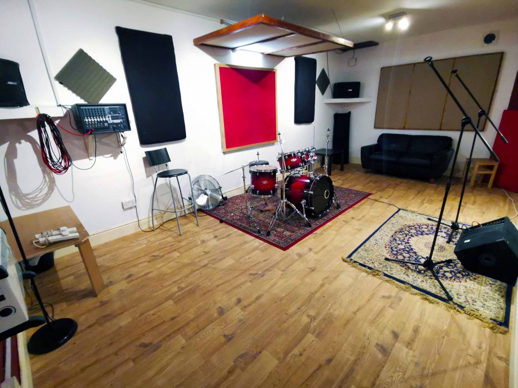 Mid size room with wooden floor, large wall Mirrors. Bose/Yamaha PA & floor monitor. Mapex mBirch fusion size kit