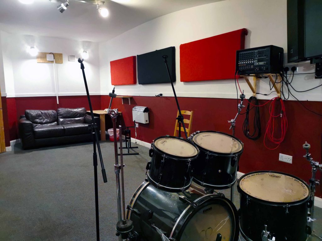 Mid size room with carpet floor. No mirrors. EV/Yamaha PA & floor monitor. Pearl EX rock/fusion size kit.
