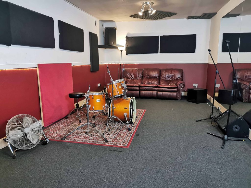 Large room with carpet floor, large wall Mirrors. EV/Yamaha PA & floor monitor. Pearl Session fusion size kit.
